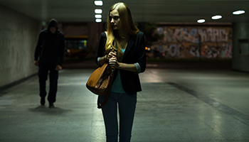 A woman walks in a shadowy tunnel
